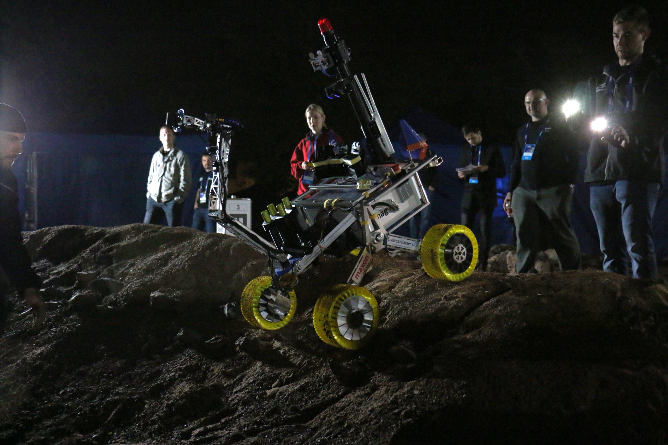 The FHNW Rover climbing rocks during the European Rover Challenge night-navigation task, lit by a single spotlight