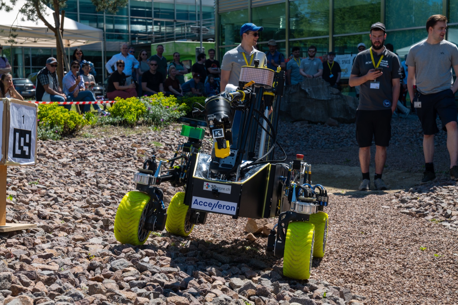 The FHNW Rover working a task on the rocky course — manipulator arm, sensor mast and yellow airless wheels
